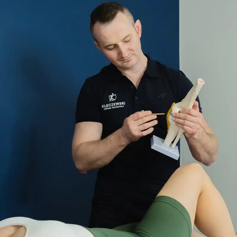 Fizjoterapeuta omawia budowę stawu kolanowego na modelu anatomicznym podczas diagnostyki fizjoterapeutycznej